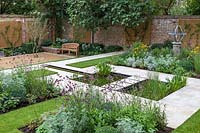 View of formal pond with rill, surrounded by mixed beds with Armillary Sundial in walled city garden.  Garden design by Peter Reader Landscapes.