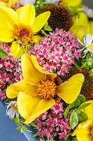 Close up of floral arrangement, with pink Sedum flower heads and yellow daisy-type blooms