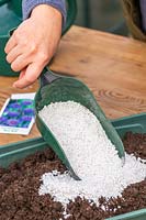 Woman adding perlite to compost to make it light and free-draining.