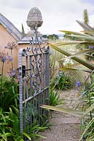 Gate from the courtyard into the wider garden framed by phormiums, agapanthus and echiums