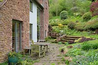 Terrace with table and chairs at back of house with ground cover planting, Ross-on-Wye