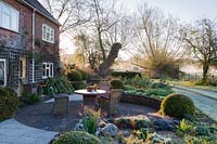 Front garden with seating, clipped box spheres, euphoribas and irises, Stockbridge, Hampshire