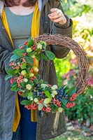 Holding autumnal deocrative wreath, with hop flowers, Cotoneaster and sloes.