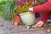 Woman setting ceramic plant pot on matching pot feet.