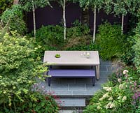 Overview of table and bench in small urban garden. Garden design by John Davies Landscape.