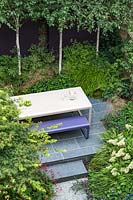 Overview of small urban garden, with raised terrace and table and bench. Garden design by John Davies Landscape.
