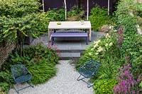 Contemporary garden table and bench and a pair of metal chairs in small urban garden. Designed by John Davies Landscapes.