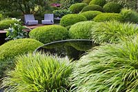 Pool and seats with clipped Buxus and Hakonechloa.  Irish Sky Garden, RHS Chelsea Flower Show