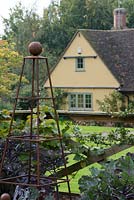View of house from the vegetable garden with a metal pyramid support in late September. Brookside