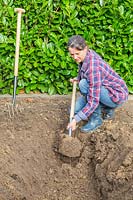 Woman digging trench in empty border.