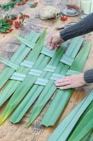 Woman weaving phormium leaves to create decorative table mat.