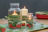 View of woven Phormium table mat and glass candle holders, decorated with Cotoneaster berries.