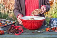 Woman adding nuts and seeds to lard in enamel mixing bowl to make bird feeder bundt cake.