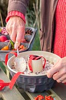 Woman using spoon to smooth bird feed mixture in bundt cake tin.