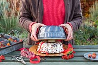 Woman lifting bundt cake tin to reveal bird feed bundt cake, made from lard, raisins and nuts.