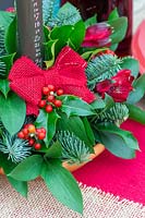 Close up of Christmas advent candle arrangement, with blue pine, ruscus, Ilex - Holly, and red Alstromeria flowers.