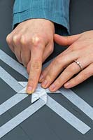Woman folding strips of decorative paper to make 3D star decoration.