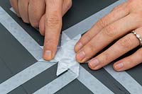 Close up of woman folding strips of decorative paper to make 3D star decoration.