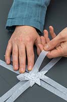 Woman folding strips of decorative paper to make 3D star decoration.