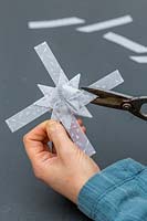 Woman trimming excess paper off 3D star decoration.