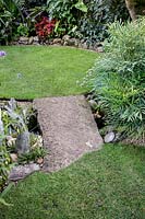 Simple stone slab forms a bridge over the stream to link both lawns.