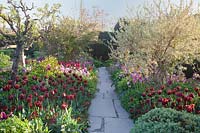 Stone path through colourful mixed borders. Great Dixter Gardens, Sussex, UK.