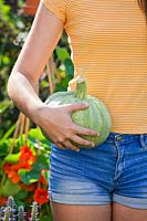 Woman holding recently harvested pumpkin.