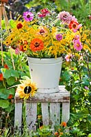 Bucket of summer flowers on crate in colourful cutting garden.
