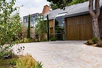 Contemporary house with circular stone sett driveway with edged with planted beds


