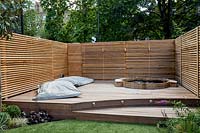 Contemporary garden surrounded by a cedar battened trellis screen for privacy around a stepped decking area with 

hot tub and large garden lounge cushions