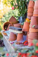 Washed terracotta pots stacked on wooden table to dry.