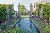 Pool and Italianate water fountains in The Collector Earl's Garden with alliums, iris and Alchemilla mollis. Arundel Castle, Sussex, UK