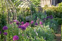 Rustic arbour with alliums and mixed planting. Arundel Castle, West Sussex, UK