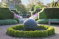 Stone sphere water feature with clipped circular hedge 