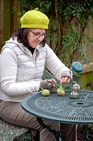 Woman taking netting off fat balls and filling a bird feeder.