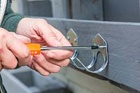 Woman using screwdriver to fix hooks on to pallet organiser. 