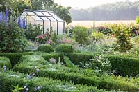 Early morning in the garden with dew marked cobwebs on the Buxus - box - edging
, view towards roses, delphiniums and greenhouse