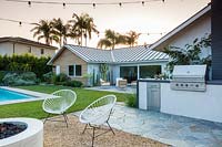 View across garden with carnival string lights to swimming pool and outside seating area. Garden designed by Falling Waters Landscape, inc Ryan Prange, New Port Beach, California, USA.