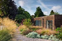 Mixed border of perennials and ornamental grasses in front of contemporary house
 