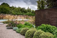 View across mixed borders to swimming pool in contemporary garden. Designed Elks-Smith Garden Design.
