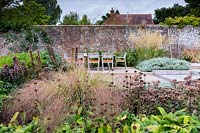 View across mixed border to outdoor table and chairs in contemporary country garden near Winchester, Hants, UK. Designed Elks-Smith Garden Design. 