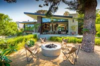 View of leather butterfly chairs and circular fire pit in eclectic Californian retro-style garden. Designed by Ryan Prange, California, USA. 