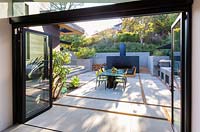 View through open bi-folding patio doors to table and chairs in garden 