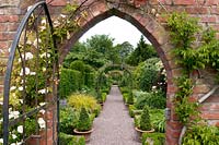View through brick archway and gate to Buxus - Box edged borders of the Long Border at Wollerton Old Hall, Shropshire, UK.
