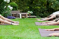People practicing yoga in garden. 

