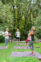 People talking after Yoga class in summer garden.
