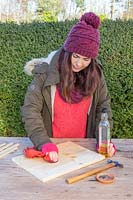 Woman rubbing vegetable oil into wood to protect it from rain.