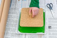 Woman lowering cork stamping pad into green paint.