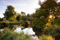 The Lower Pond adjoining the Round Garden is surrounded by trees and shrubs. Llanover Gardens, Monmouthshire, UK. 