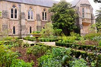 The East Garden laid out with beds of herbaceous perennials, roses and apple trees edged with euonymus hedging at the Bishop's Palace Garden, Wells, Somerset, UK